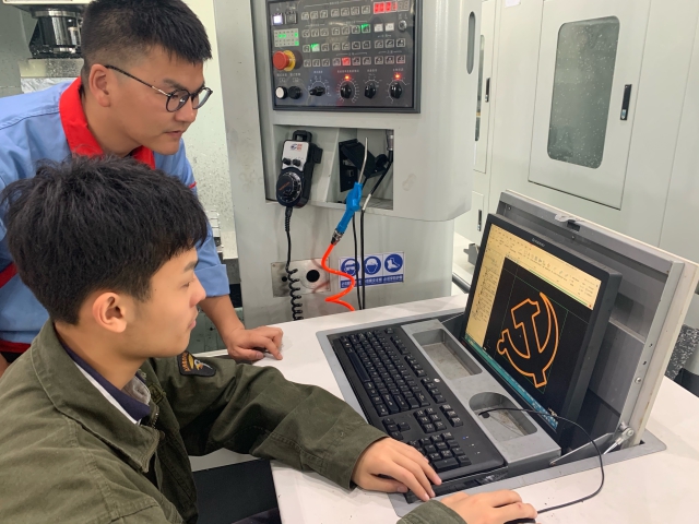 圖為黨員青年教師高飛正指導學生用數控車床制作黨徽 學校供圖.jpg