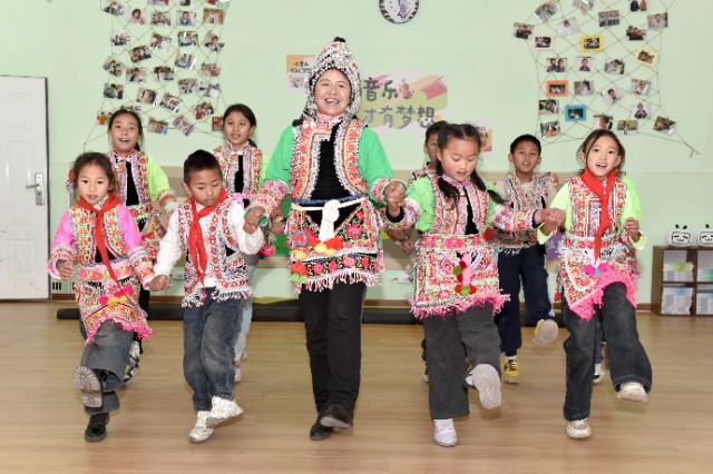 馬游小學(xué)社團(tuán)課上，梅葛文化國家級(jí)傳承人羅英老師教學(xué)生邊唱娃娃梅葛調(diào)邊跳彝族舞蹈。（蔡興華  攝影）.JPG